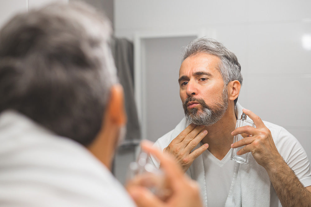 Man in the bathroom using cologne